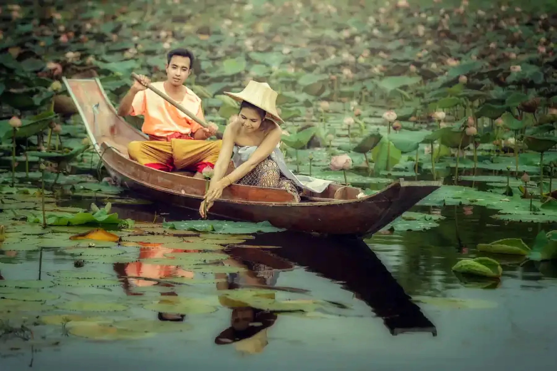 Deux voyageurs en barque au milieu des feuilles de lotus