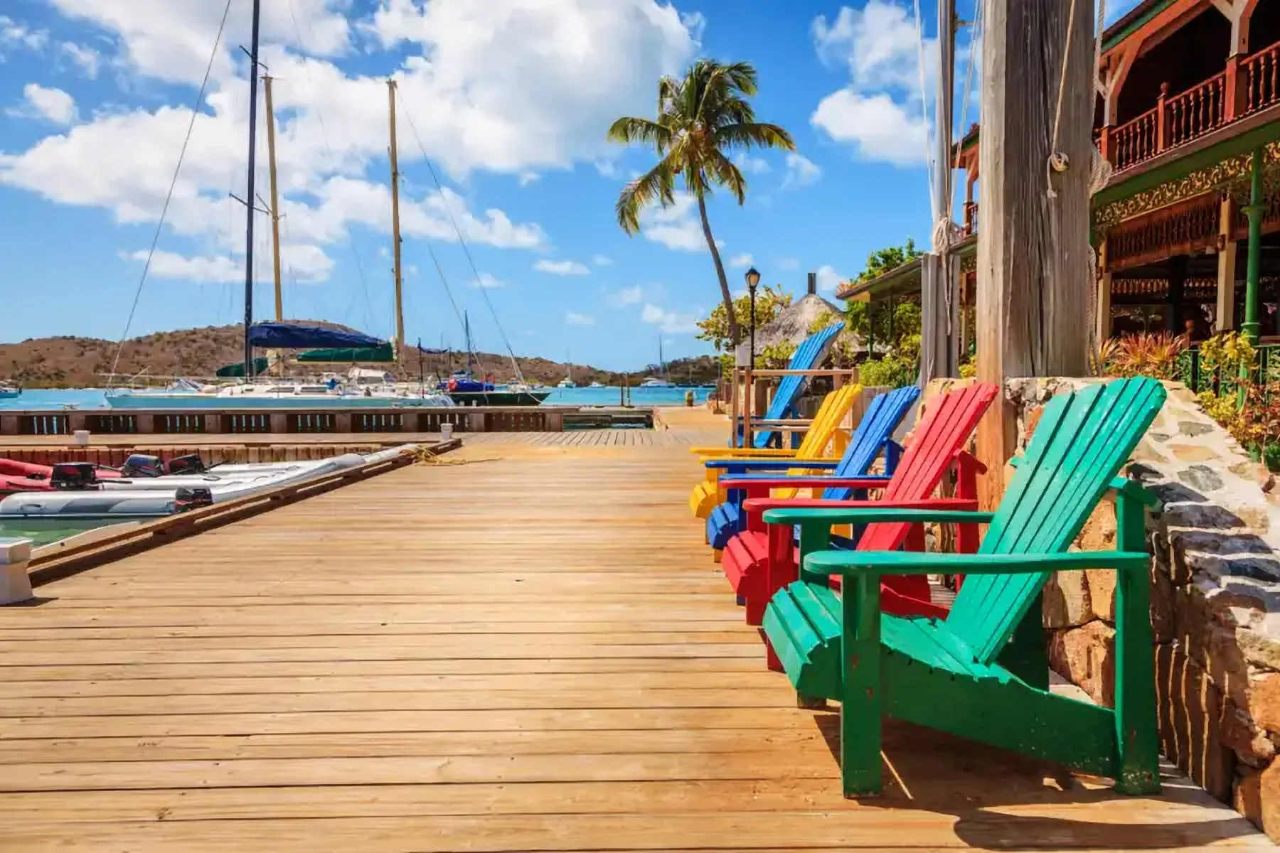 Chaises longues colorées sur un ponton face à une marina
