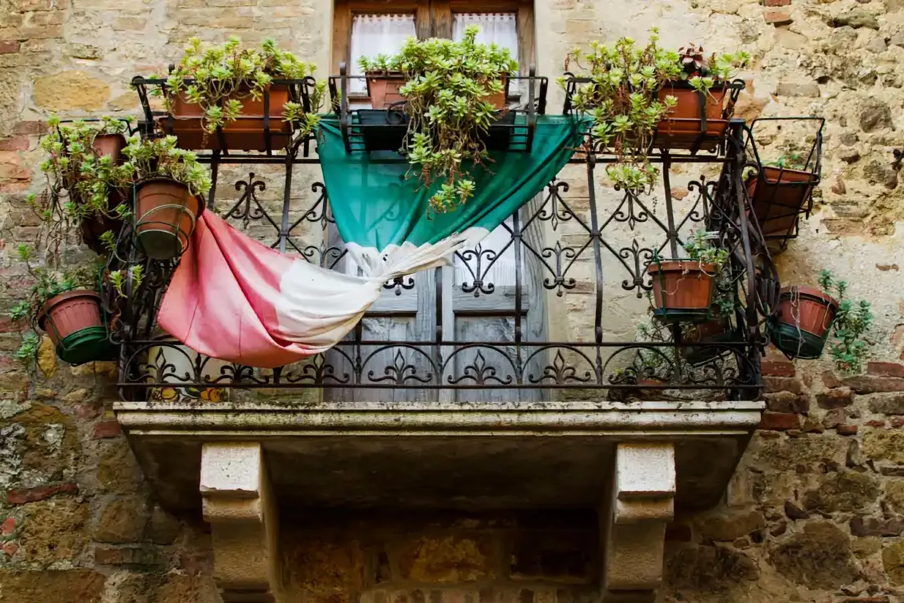 Un balcon de pierre fleuri, drapé d’un drapeau